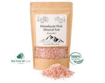 Op de afbeelding: Een bruine papieren zak met roze Himalaya mineraalzoutkorrels. Het etiket bevat een bergafbeelding, de tekst Himalayan Pink Mineral Salt (Granules) en de website www.treeoflove.shop. Een hoopje roze zout ligt voor de zak.