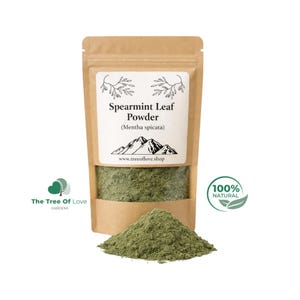 May include: A brown kraft paper stand-up pouch containing green spearmint leaf powder. The white label features the text Spearmint Leaf Powder, Mentha spicata, a mountain graphic, and the website www.treeoflove.shop. A pile of the powder sits in front.