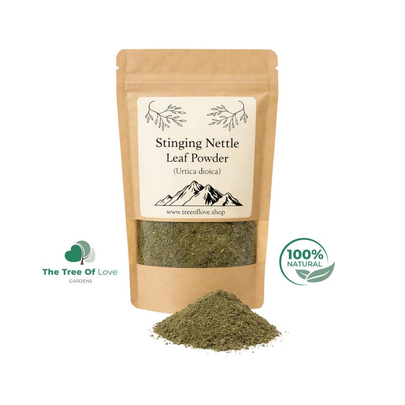 May include: A brown kraft paper pouch containing Stinging Nettle Leaf Powder, labeled with the text Stinging Nettle Leaf Powder (Urtica dioica) and a mountain graphic. A small pile of the fine, dark green powder sits in front of the pouch.