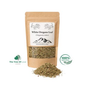 May include: A brown paper pouch containing dried white oregano leaves, labeled with the text White Oregano Leaf (Origanum onites) and a mountain graphic. A pile of the dried green herb sits in front of the pouch, which has a clear window.