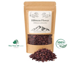 May include: A brown paper pouch containing dried dark red hibiscus flowers. The white label features the text Hibiscus Flower (Hibiscus sabdariffa), a mountain graphic, and the website www.treeoflove.shop. A pile of loose dried flowers sits in front.