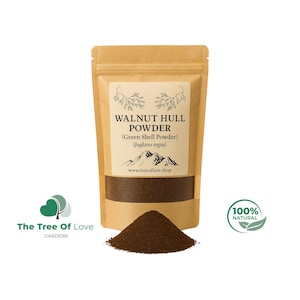 May include: A brown kraft paper pouch of walnut hull powder with a label that reads "WALNUT HULL POWDER (Green Shell Powder) (Juglans regia)". A small pile of the powder sits in front of the pouch. The words "100% NATURAL" are on the right.