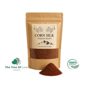 Op de afbeelding: Een bruine papieren zak met gedroogde maïshaar, met een etiket met de tekst CORN SILK (Stigmata Maydis) en www.treeoflove.shop. Een kleine hoop roodbruine, draadachtige maïshaar ligt voor de zak op een witte achtergrond.