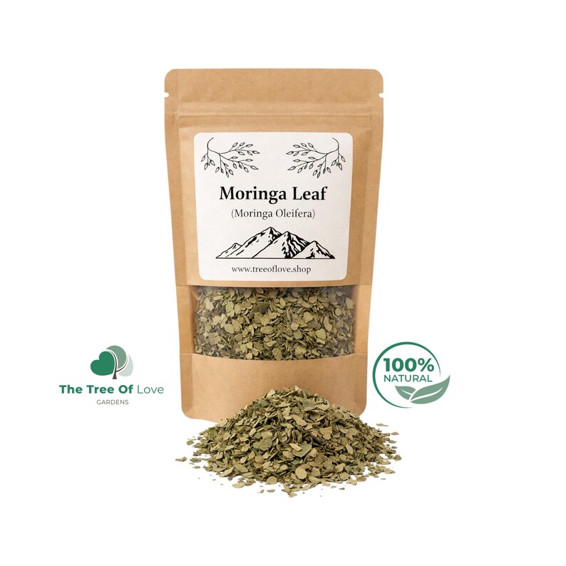 May include: A brown kraft paper stand-up pouch containing dried Moringa Leaf (Moringa Oleifera). The label features a mountain graphic, the text "Moringa Leaf (Moringa Oleifera)" and "www.treeoflove.shop". A pile of dried green leaves sits in front.
