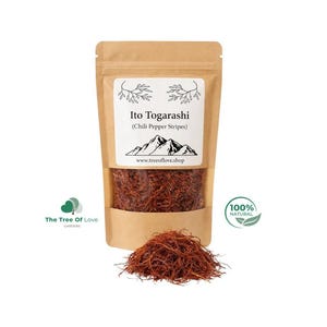 Può includere: Un sacchetto di carta marrone contenente strisce di peperoncino rosso etichettate Ito Togarashi con un grafico di montagna e il testo www.treeoflove.shop. Un piccolo mucchio di strisce di peperoncino rosso si trova davanti al sacchetto.