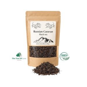 Puede incluir: Una bolsa de papel kraft marrón de té negro Russian Caravan con una ventana transparente que muestra hojas de té oscuras. La etiqueta presenta un gráfico de montaña, el texto Russian Caravan black tea y www.treeoflove.shop. Té suelto al frente.