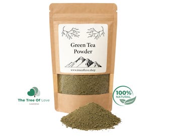 May include: A brown kraft paper pouch containing green tea powder with a clear window showing the contents. The label features the text Green Tea Powder, a mountain illustration, and the website www.treeoflove.shop. A pile of green tea powder sits in front.