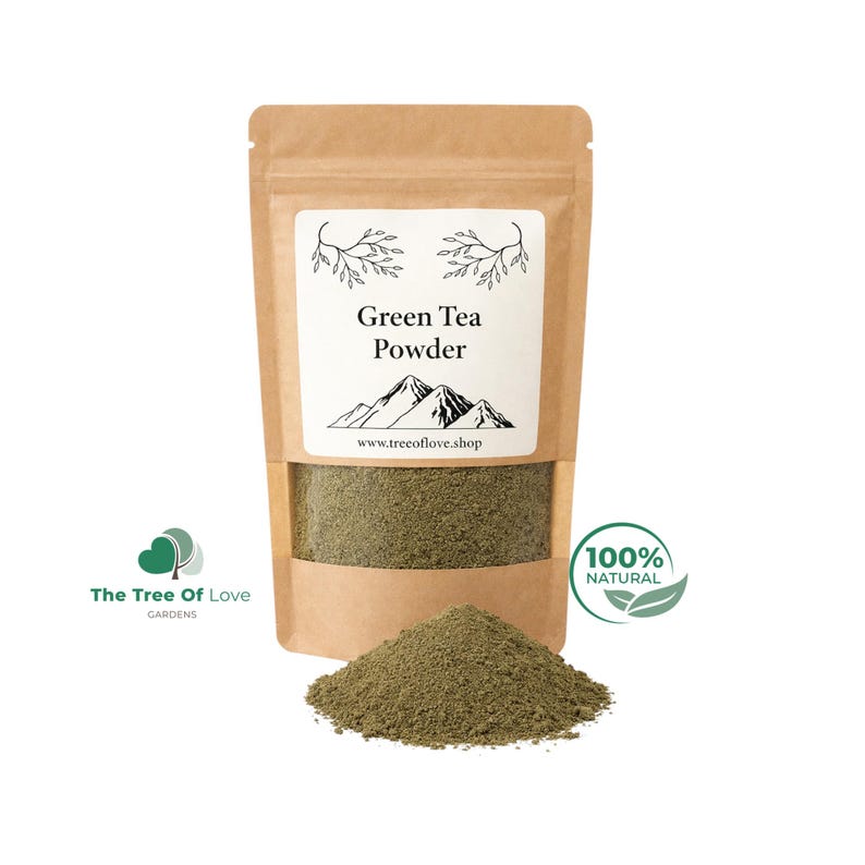 May include: A brown kraft paper pouch containing green tea powder with a clear window showing the contents. The label features the text Green Tea Powder, a mountain illustration, and the website www.treeoflove.shop. A pile of green tea powder sits in front.
