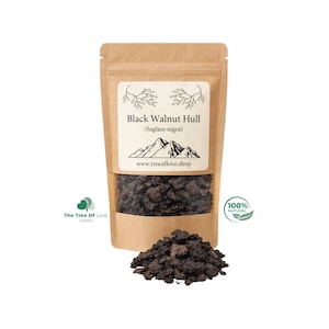 Puede incluir: Una bolsa de papel kraft marrón que contiene trozos de cáscara de nogal negro texturizados de color marrón oscuro. La etiqueta muestra el texto Black Walnut Hull (Juglans nigra), un gráfico de montaña, la web www.treeoflove.shop y un logo 100% natural.
