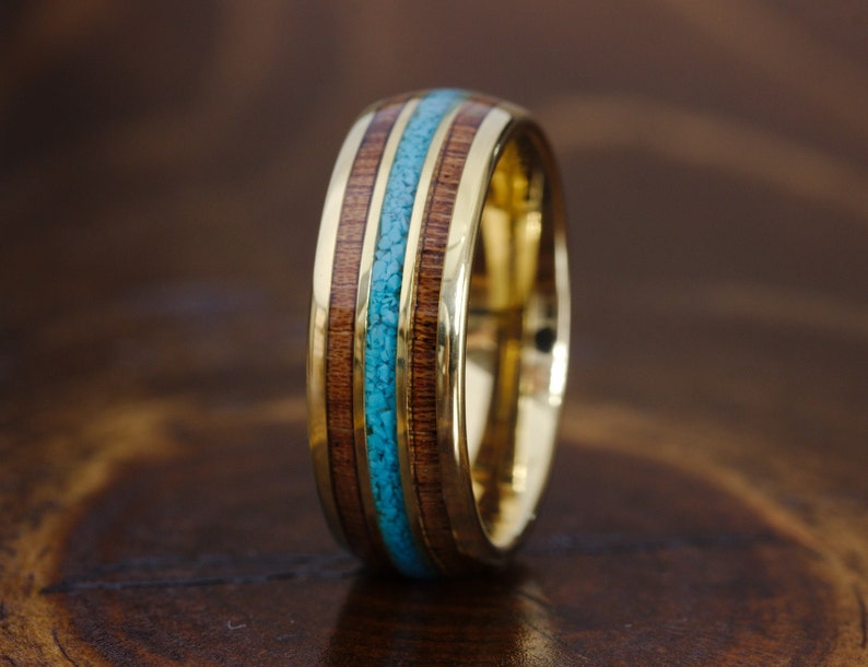 May include: A gold band with a turquoise and wood inlay. The band is made of metal and has a polished finish.