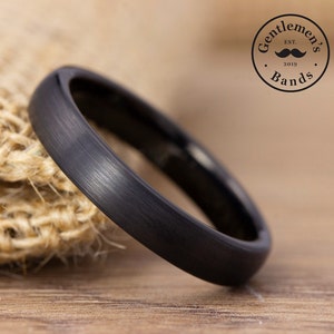 May include: A black tungsten carbide ring with a brushed finish. The ring is simple and elegant, and it would make a great wedding band or promise ring.