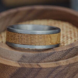 May include: A silver and wood ring with a wood inlay. The ring is in a wooden box.