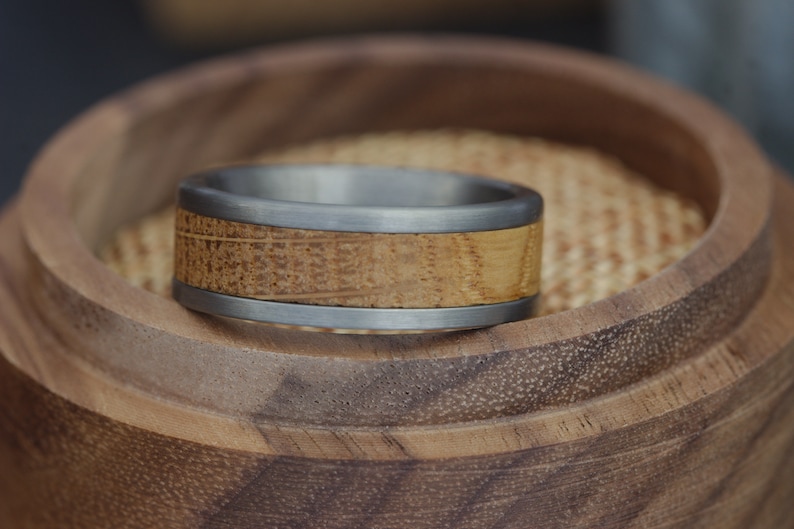 May include: A silver and wood ring with a wood inlay. The ring is in a wooden box.