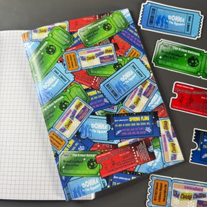 May include: A notebook with a cover adorned with a vibrant collage of vintage ticket stubs. The tickets, in shades of green, blue, red, and yellow, display text like "Donna & The Dynamos" and "Spring Fling", evoking a retro aesthetic.
