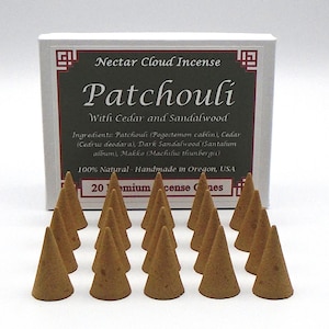 May include: A box of 20 brown incense cones with the text "Nectar Cloud Incense Patchouli With Cedar and Sandalwood" on the front. The box is white with a red border and a small gray square in the top right corner. The ingredients are listed on the box: Patchouli (Pogostemon cablin), Cedar (Cedrus deodara), Dark Sandalwood (Santalum album), Makko (Machilus thunbergii). The box also states that the incense is 100% natural and handmade in Oregon, USA.