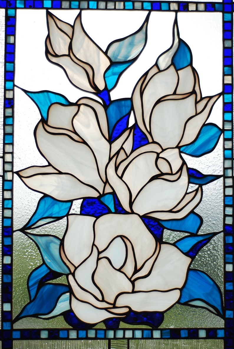 Puede incluir: Una ventana de vitrales que representa flores blancas con hojas azules y un borde azul.