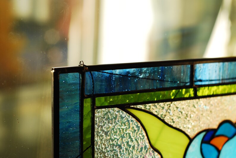 May include: A stained glass window panel with a floral design. The panel features blue, green, and yellow glass pieces. The glass is textured and has a frosted appearance.