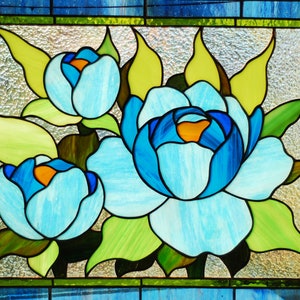 May include: A stained glass window depicting three blue flowers with yellow centers and green leaves.