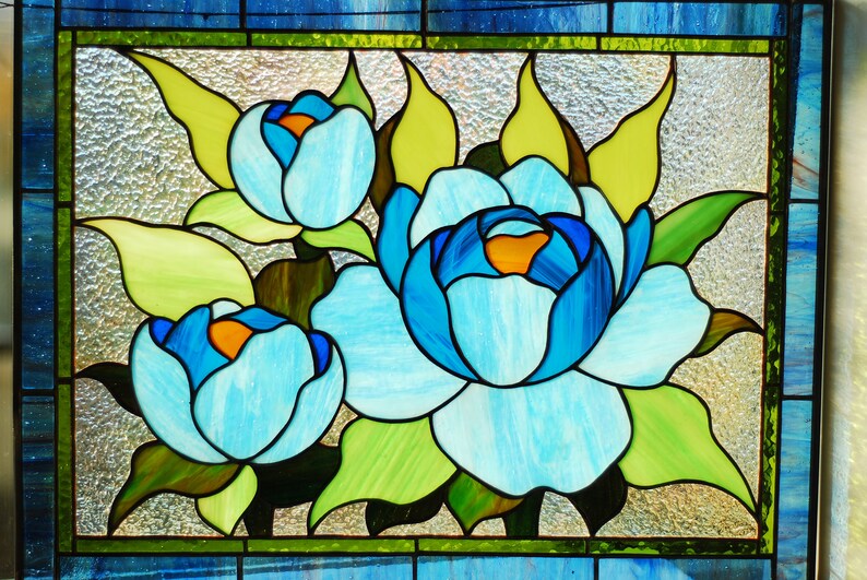 May include: A stained glass window depicting three blue flowers with yellow centers and green leaves.