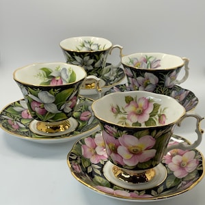 May include: Four teacups and saucers with floral patterns. The cups and saucers are white with gold trim. The floral patterns are in shades of pink, green, and white. The cups are all different, but they all have a similar style.
