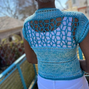 Puede incluir: Un top de crochet con un diseño degradado en azul y verde. El top tiene una gran espalda abierta con un patrón de crochet. El top es sin mangas y tiene un corpiño ajustado.