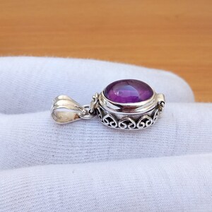 May include: A silver locket pendant with an ornate design and a purple amethyst gemstone.