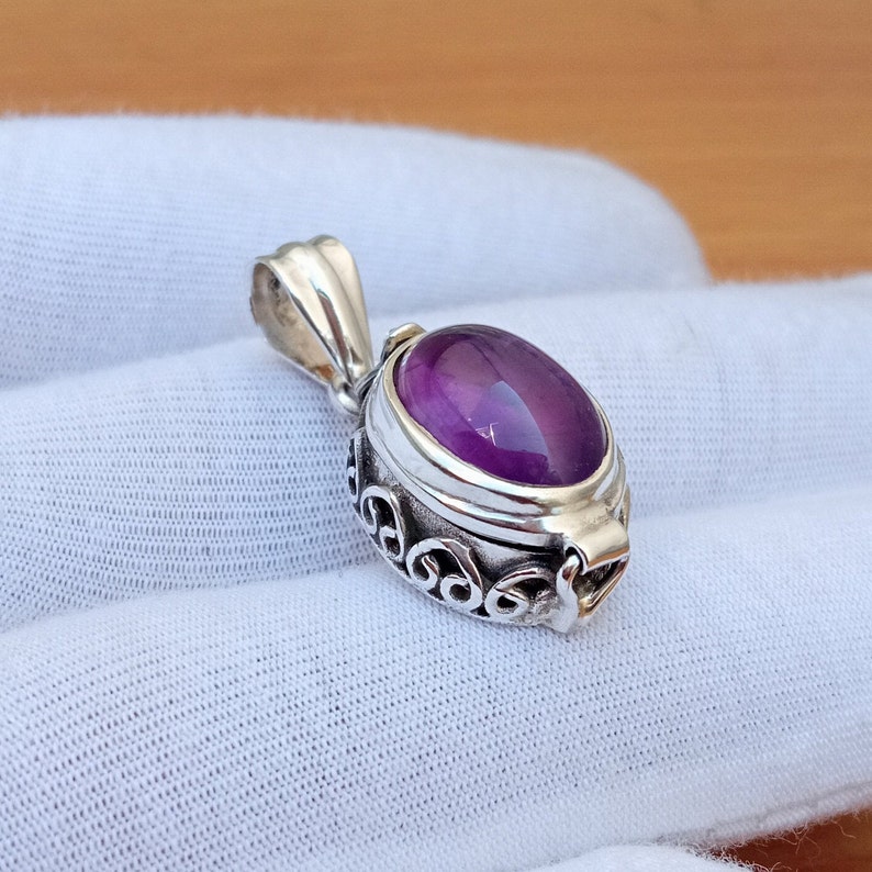 May include: A silver pendant with an ornate design and a purple amethyst stone.