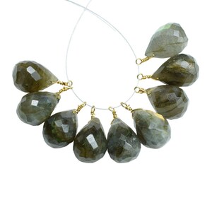Peut inclure: Un brin de 10 perles de labradorite en forme de goutte avec des boucles de fil dorées. Les perles sont de couleur vert foncé avec des reflets irisés.
