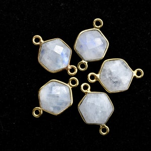 May include: Five hexagonal moonstone gemstone connector charms with gold-toned jump rings. The charms are arranged in a star shape on a black background.