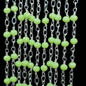 May include: A silver chain with light green glass beads. The chain is made of small, linked metal rings.