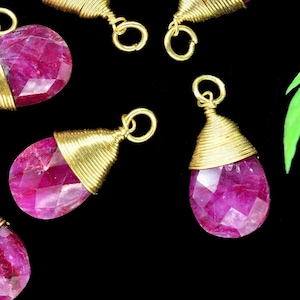 Pode incluir: Sete pingentes de pedra preciosa rosa em forma de lágrima com fio de ouro enrolado na parte superior. Os pingentes têm um design facetado e são perfeitos para a fabricação de joias.