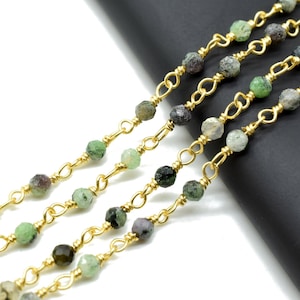 May include: Gold chain with green and black gemstone beads. The chain is made of small, linked loops of gold wire.