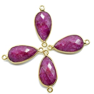 May include: Four teardrop-shaped ruby gemstone pendants with gold-toned metal loops. The gemstones are a deep, rich pink color.