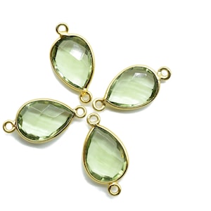 Può includere: Quattro ciondoli a forma di goccia placcati in oro con inserti di pietre preziose verdi. I ciondoli hanno un anello su ciascun lato per il fissaggio ai gioielli.