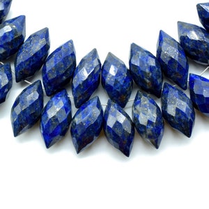 Peut inclure: Un brin de perles de lapis-lazuli facettées bleu foncé. Les perles sont en forme de marquise, ou ovale allongé, avec une extrémité pointue. Les perles sont enfilées sur un fil d'argent.