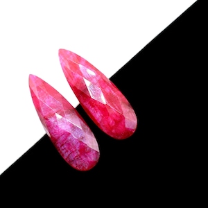 May include: Two teardrop-shaped pink gemstones with faceted surfaces.