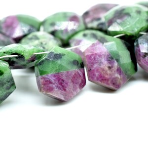 May include: A strand of faceted green and pink gemstone beads. The beads are irregularly shaped and have a mottled appearance.
