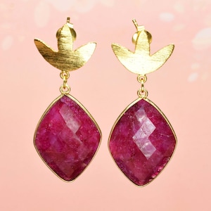 Puede incluir: Un par de pendientes colgantes con un diseño de hoja de oro y una gran piedra preciosa rosa facetada.