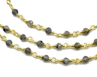 May include: A gold chain necklace with grey gemstone beads. The chain is made of small, linked loops of gold wire.