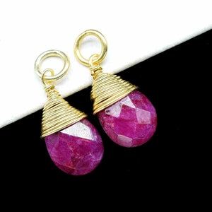Könnte beinhalten: Zwei rosa Edelstein-Tropfenanhänger mit goldfarbenem Draht, der um die Oberseite jedes Steins gewickelt ist.