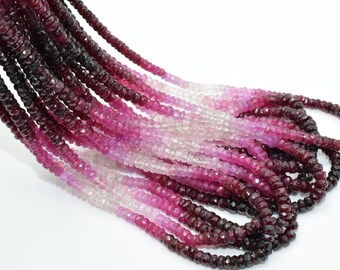 May include: A strand of faceted gemstone beads in shades of pink, red, and white. The beads are graduated in size, with the larger beads at the top and the smaller beads at the bottom. The beads are strung on a clear thread.