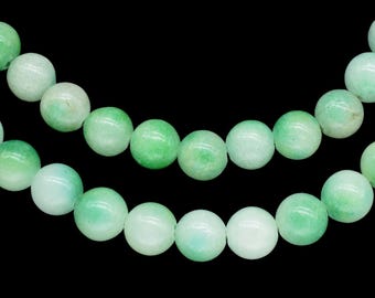 May include: Two strands of jade beads with a gradient of light to medium green hues. The beads are round and smooth, with a polished finish. The background is solid black, highlighting the jewelry.
