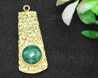 May include: Gold pendant with a textured surface and a green gemstone in the center.