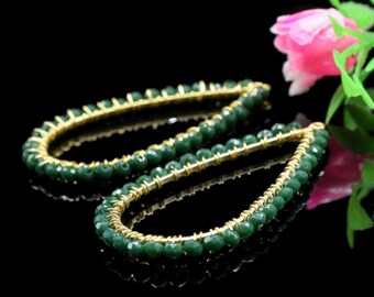 Puede incluir: Un par de pendientes de gota verde y dorado con diseño de cuentas.
