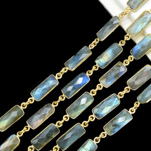 Pode incluir: Uma corrente de ouro com contas retangulares de labradorita. A corrente é feita de metal folheado a ouro e as contas são uma mistura de azul claro e escuro.