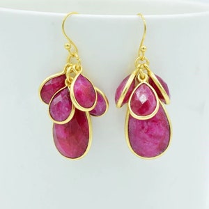 May include: Gold earrings with a cluster of pink gemstone drops.