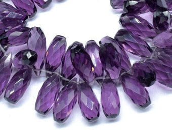 May include: Strand of faceted, teardrop-shaped amethyst beads. The beads are a deep purple color and strung together on a thin, clear cord. The beads are arranged in a circular pattern against a white background.