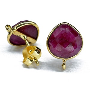 Puede incluir: Un par de pendientes de oro con gotas de piedras preciosas de color rojo rubí. Los pendientes tienen un diseño sencillo y son perfectos para el uso diario.