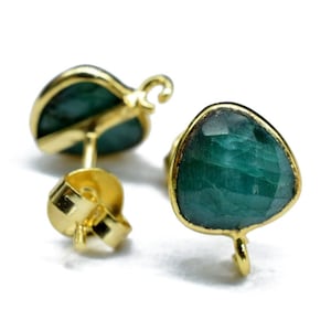 May include: A pair of gold earrings with green gemstone accents. The earrings have a simple stud design with a small, faceted gemstone.