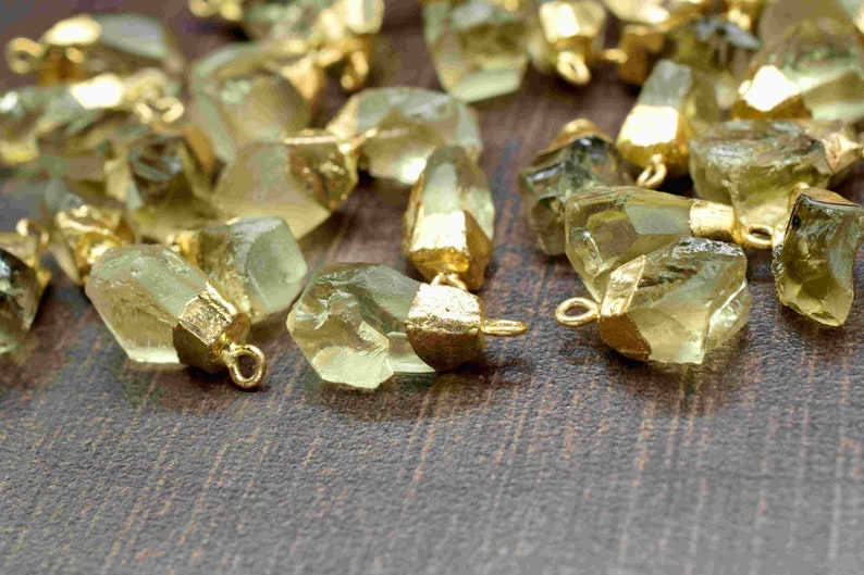 May include: A collection of green gemstone pendants with gold-plated accents. The pendants are faceted and have a natural, raw look. They are perfect for jewellery making or crafting.